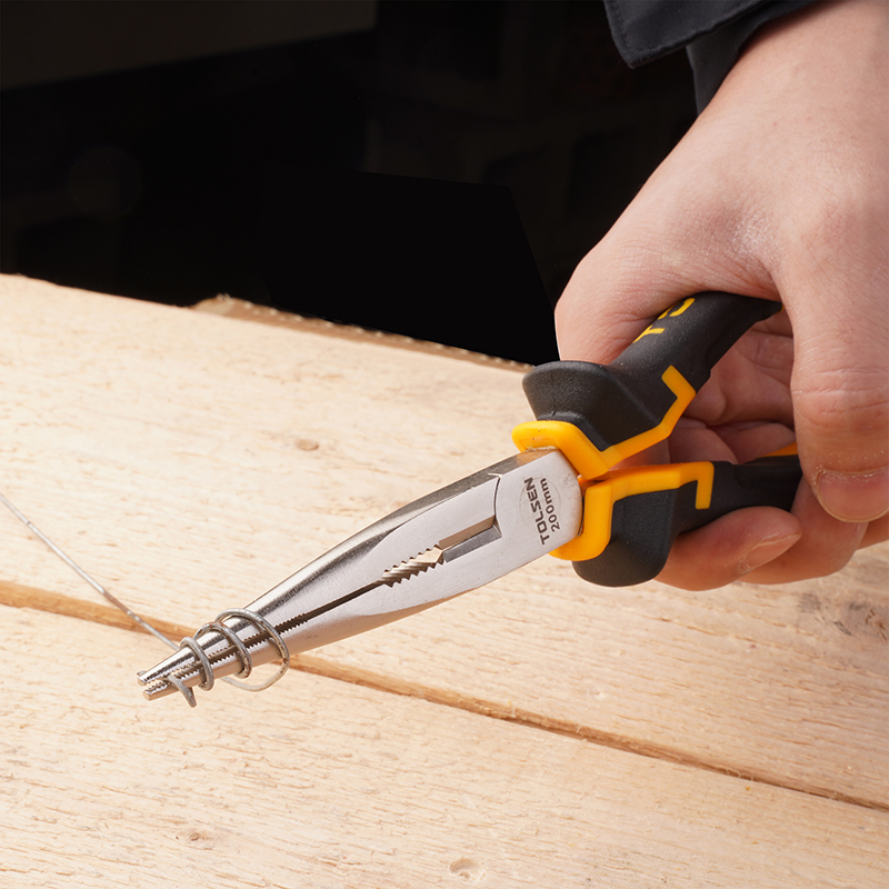 A hand holding a pair of Tolsen 200mm pliers, gripping a coiled metal wire on a wooden surface