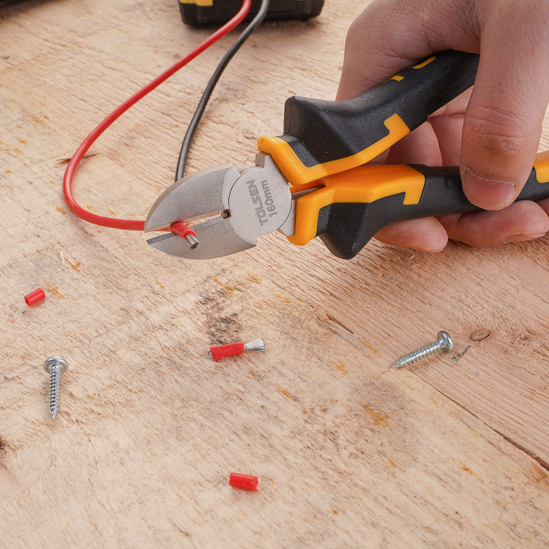 A pair of Tolsen 160mm diagonal cutting pliers being used to cut a red wire on a wooden surface