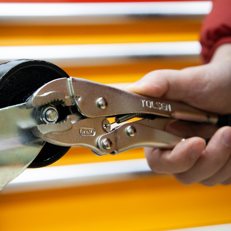 Close-up of hand holding Tolsen 10 inch locking pliers gripping metal object