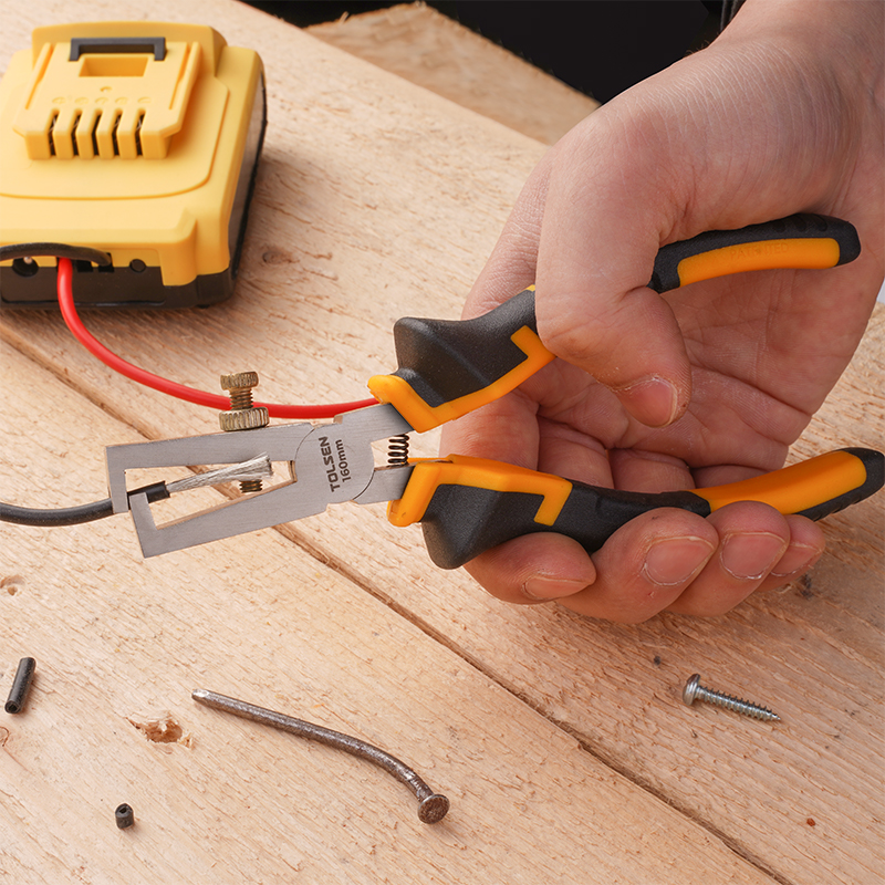 Hand using Tolsen 160mm wire stripping pliers to strip insulation from wire