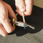 Close-up of hand using Tolsen 4.5 inch mini diagonal cutting pliers to cut bundled and stripped electrical wires