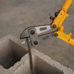 Close-up of Tolsen 24 inch bolt cutter cutting metal rod on concrete block