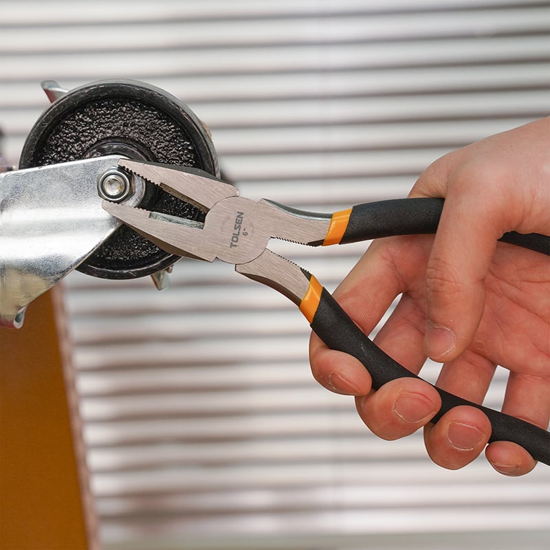 Close-up of Tolsen 6 inch combination pliers gripping bolt on metal part